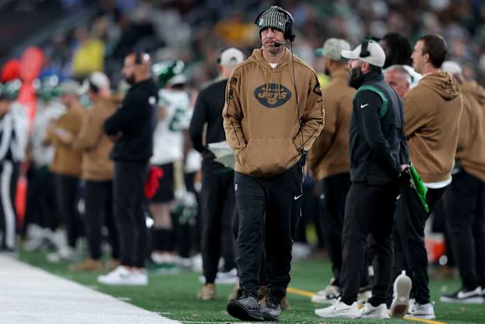 New York Jets injured quarterback Aaron Rodgers walks down the sidelines during a game.